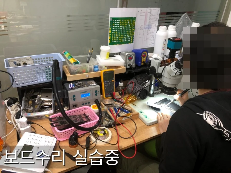 Student practicing iPhone board repair under a microscope at FIXSTORY ACADEMY, Los Angeles