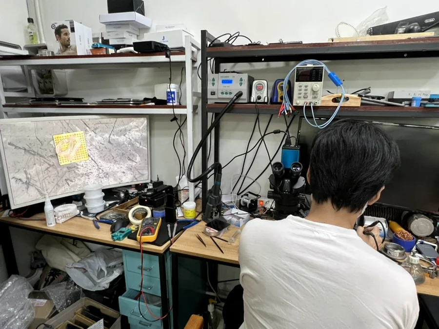 Student practicing at a phone repair soldering bench with a microscope, FIXSTORY ACADEMY