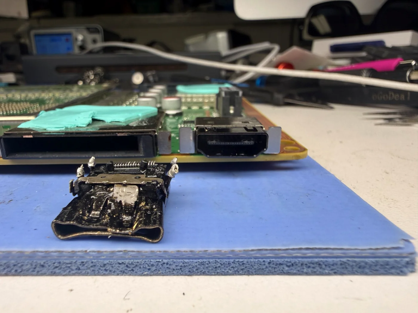 Damaged Xbox Series X HDMI port removed from the mainboard without hot air, lying in front of the board