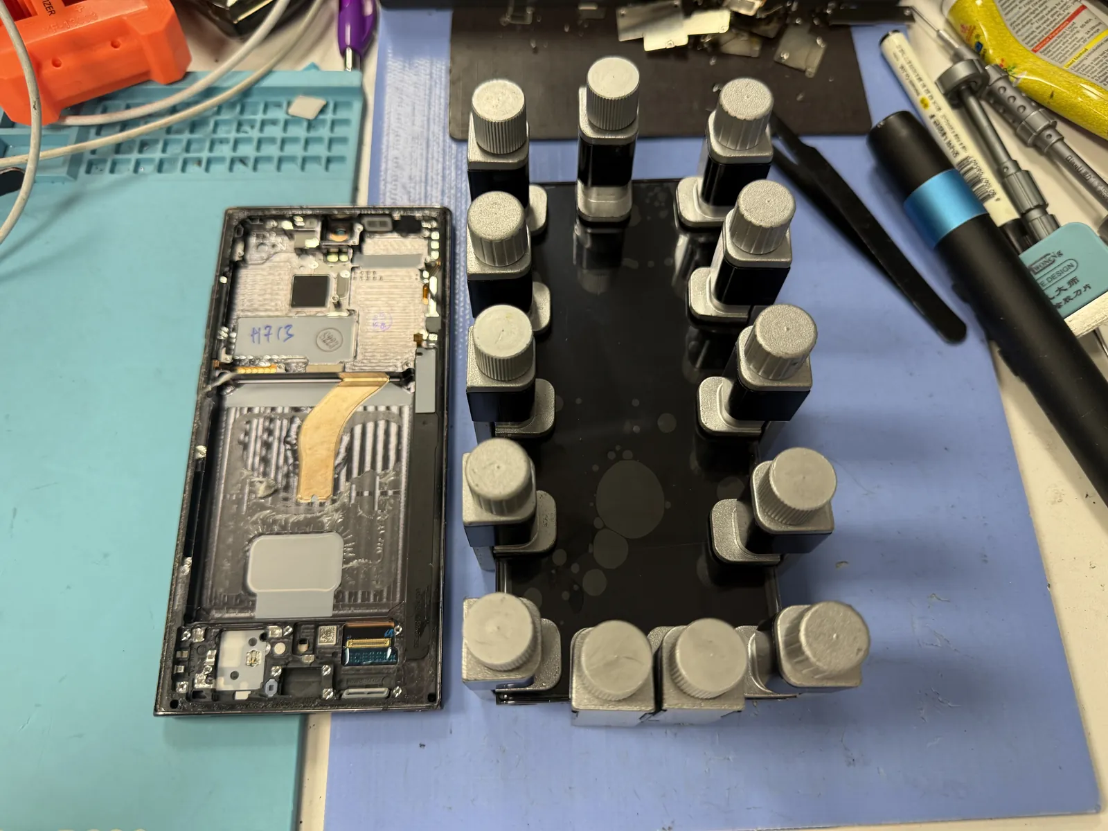 Clamps holding the Galaxy S22 Ultra back glass while the fresh adhesive cures