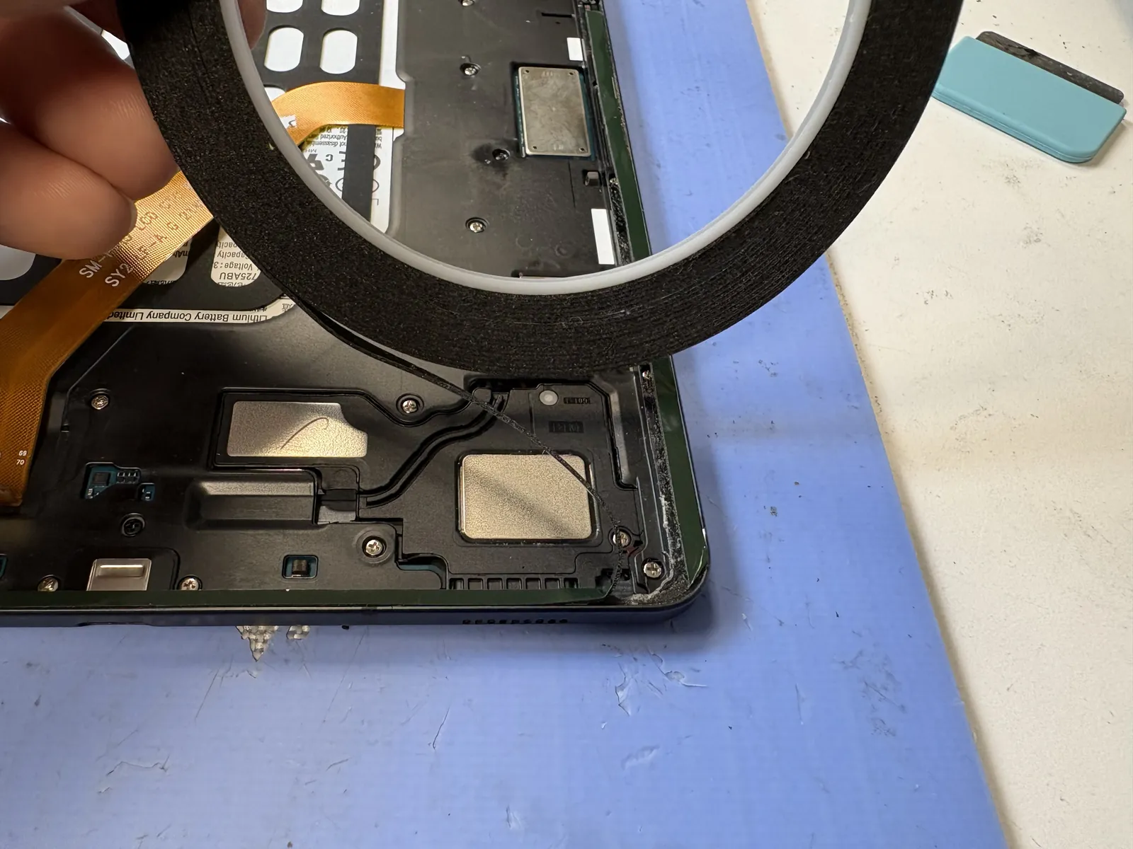 Magnifier over the corner of a Galaxy Tab S6 Lite frame while old adhesive and glass shards are cleaned out before the new screen assembly is fitted
