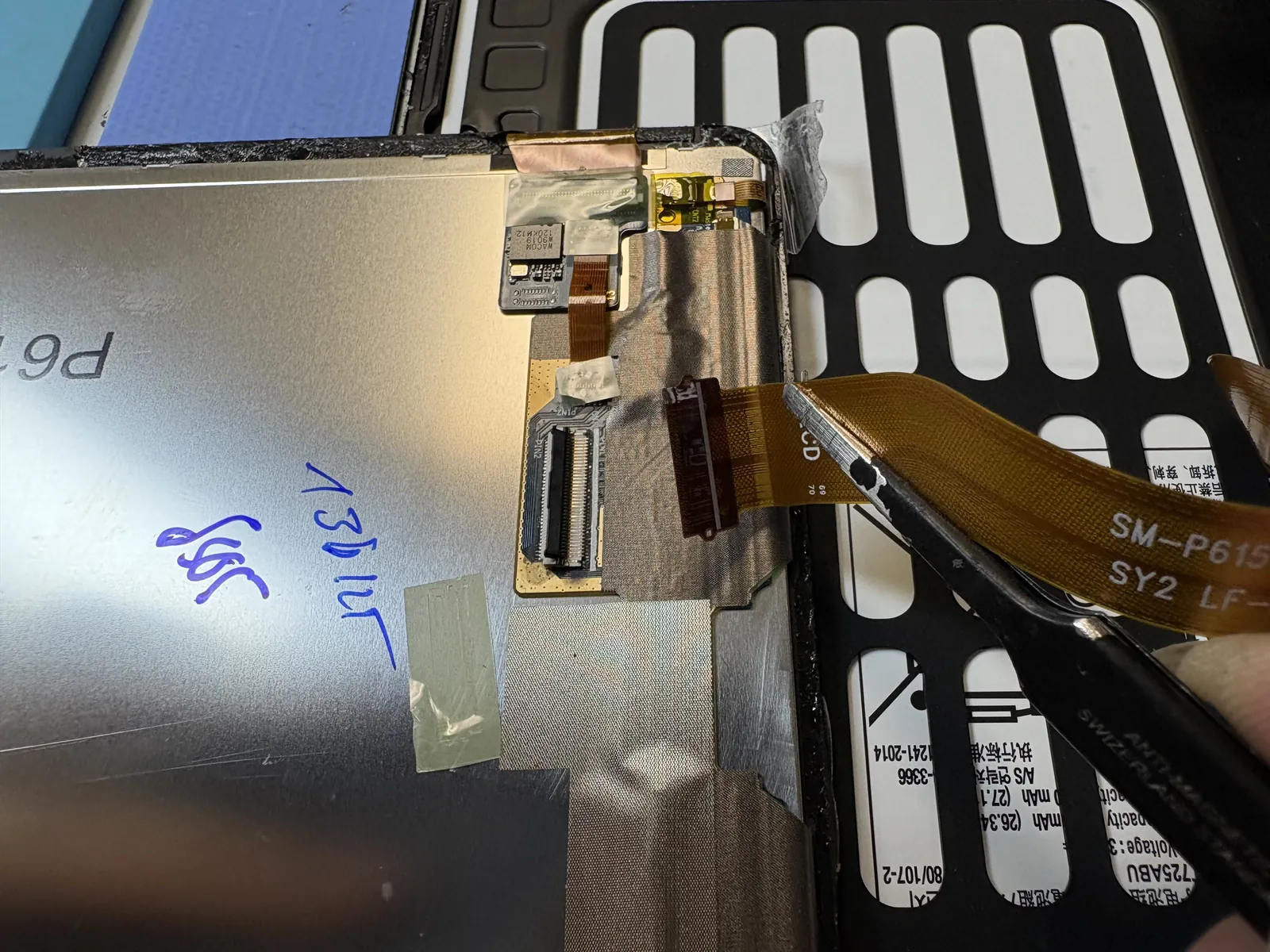 LCD flex cable being released with tweezers on a Galaxy Tab S6 Lite, next to the Wacom S Pen digitizer board