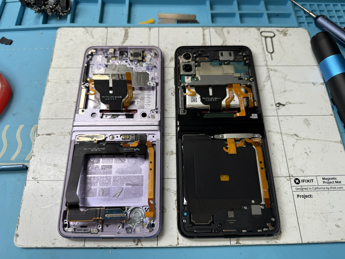 Components being transferred from the damaged Galaxy Z Flip 3 screen assembly to the genuine Samsung replacement assembly