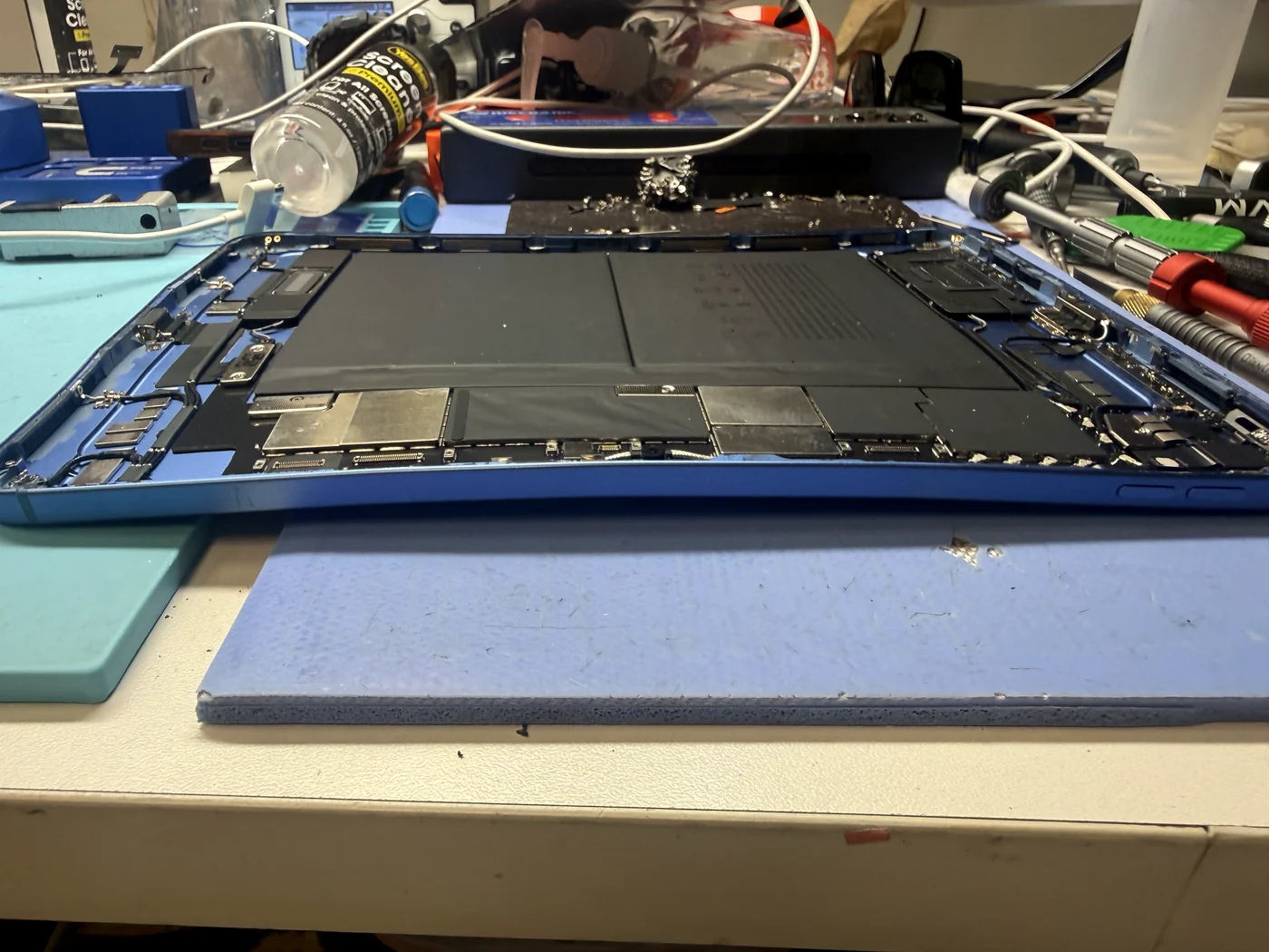 Open iPad 11-inch (2025) housing seen edge-on, the twist in the frame visible with the board and battery inside