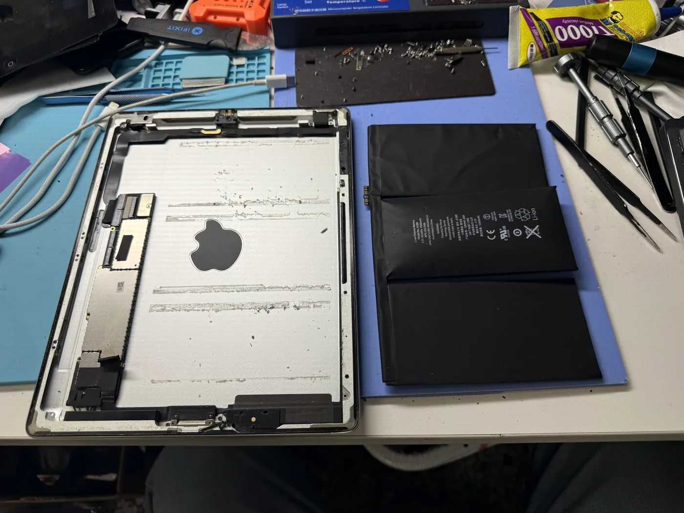 Swollen iPad 3 battery removed and laid beside the empty housing with its adhesive residue