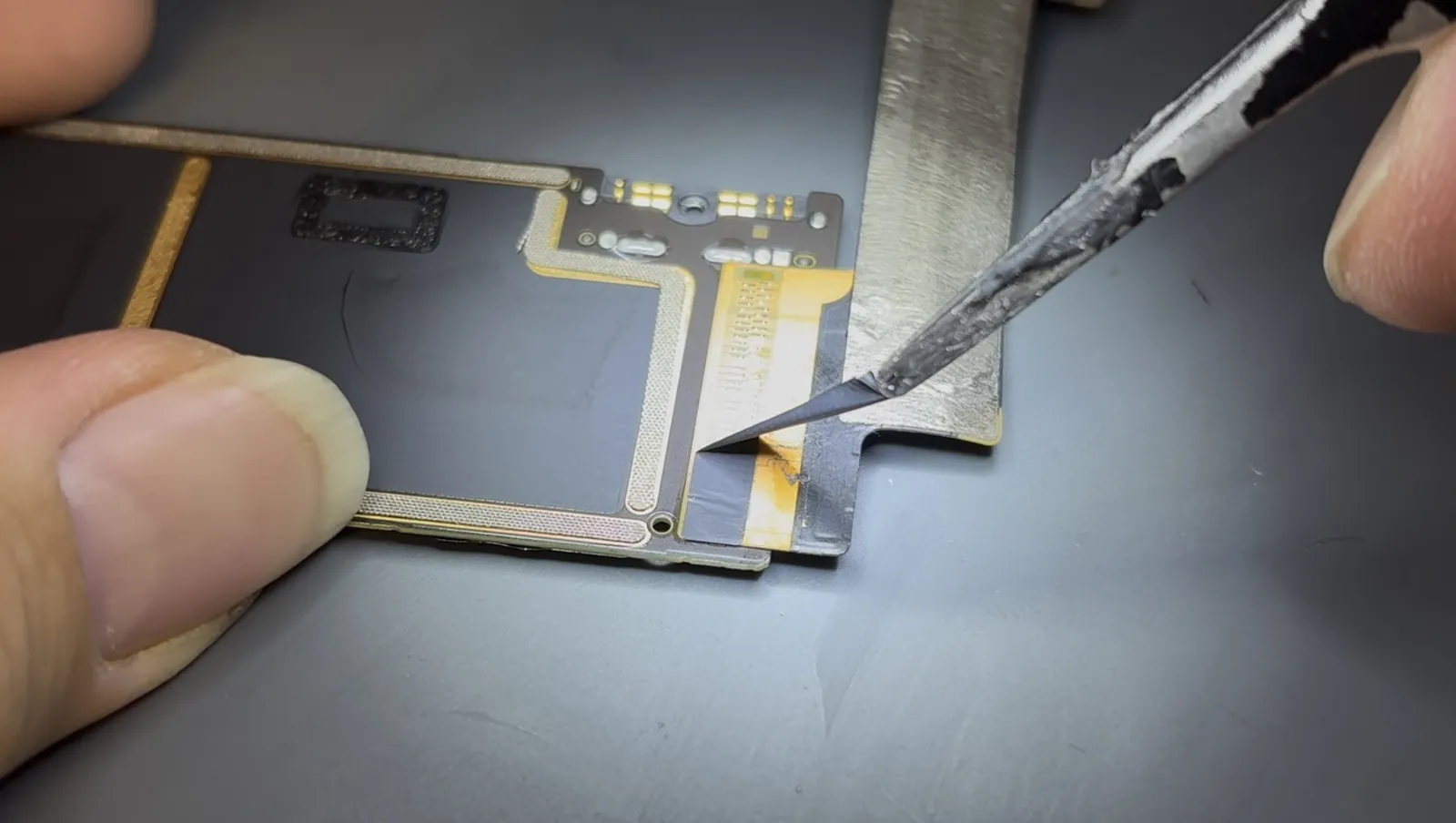 Removing the protective tape from the damaged iPad Air 4 charging port before desoldering