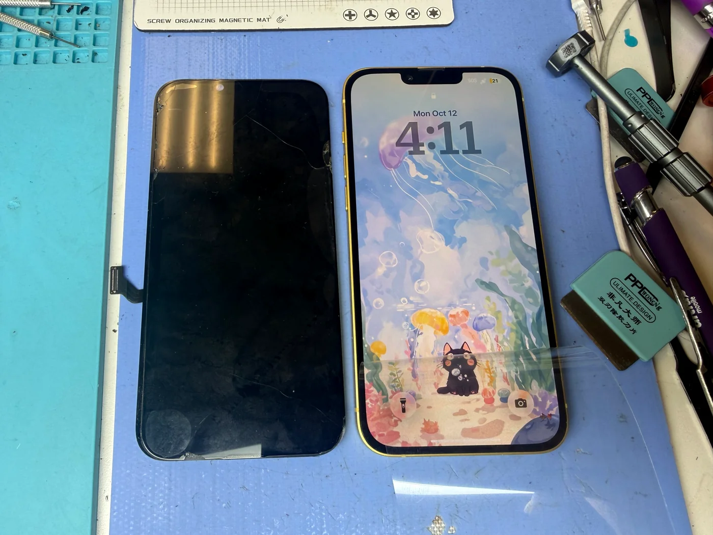 iPhone 14 Plus back on its lock screen after water damage cleaning and OLED screen replacement, next to the old damaged screen, at FIXSTORY in Downtown Los Angeles