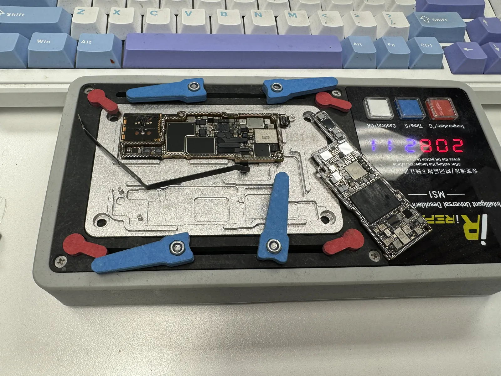 iPhone 14 Pro logic board with its two layers separated on a temperature-controlled desoldering platform
