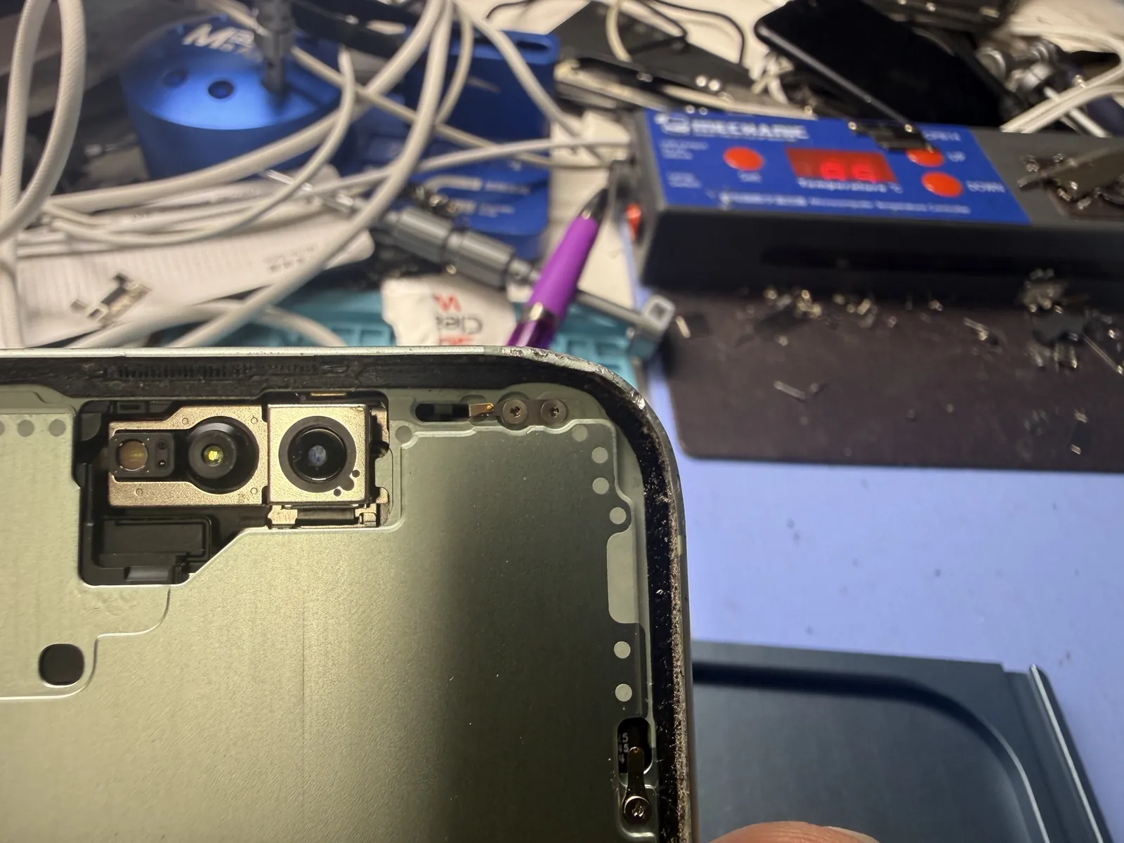 Close-up of the dented corner on an iPhone 15 frame with the screen removed, before straightening