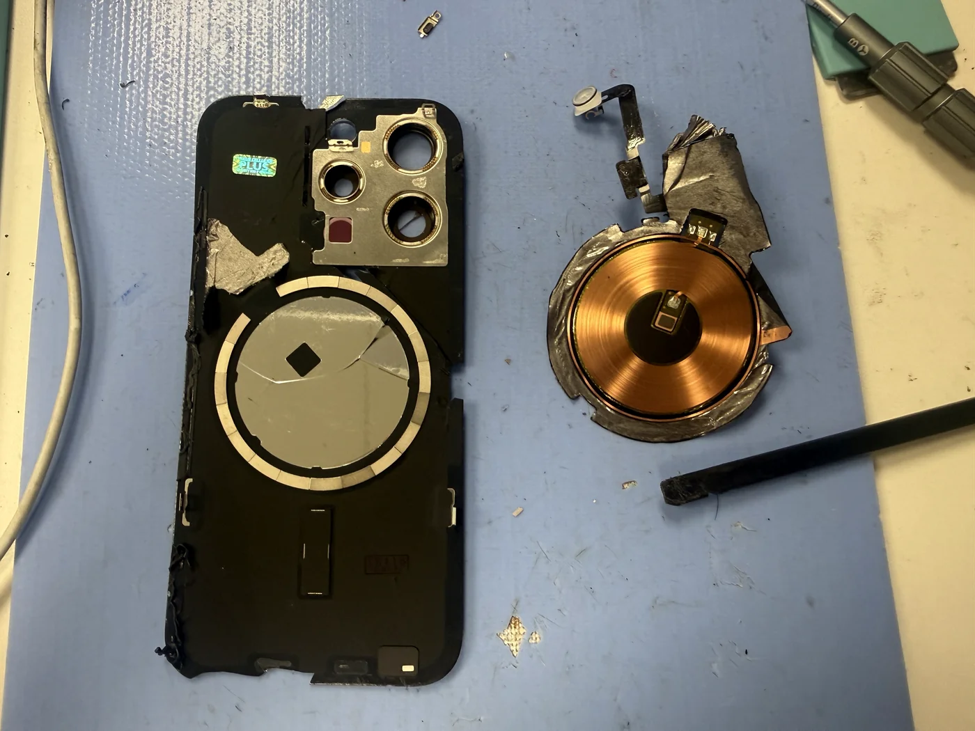 Inside of the removed back glass with the MagSafe wireless charging coil and flash flex detached for transfer