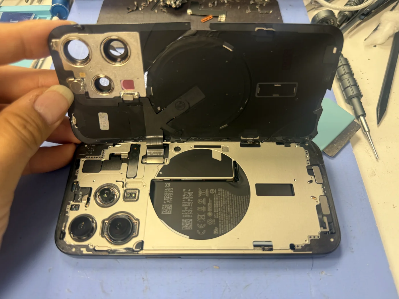 iPhone 15 Pro back glass lifted away from the frame, battery and inner frame exposed