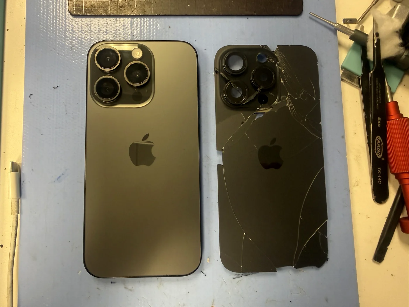 iPhone 15 Pro with the customer-supplied aftermarket back glass fitted, next to the cracked panel that was removed