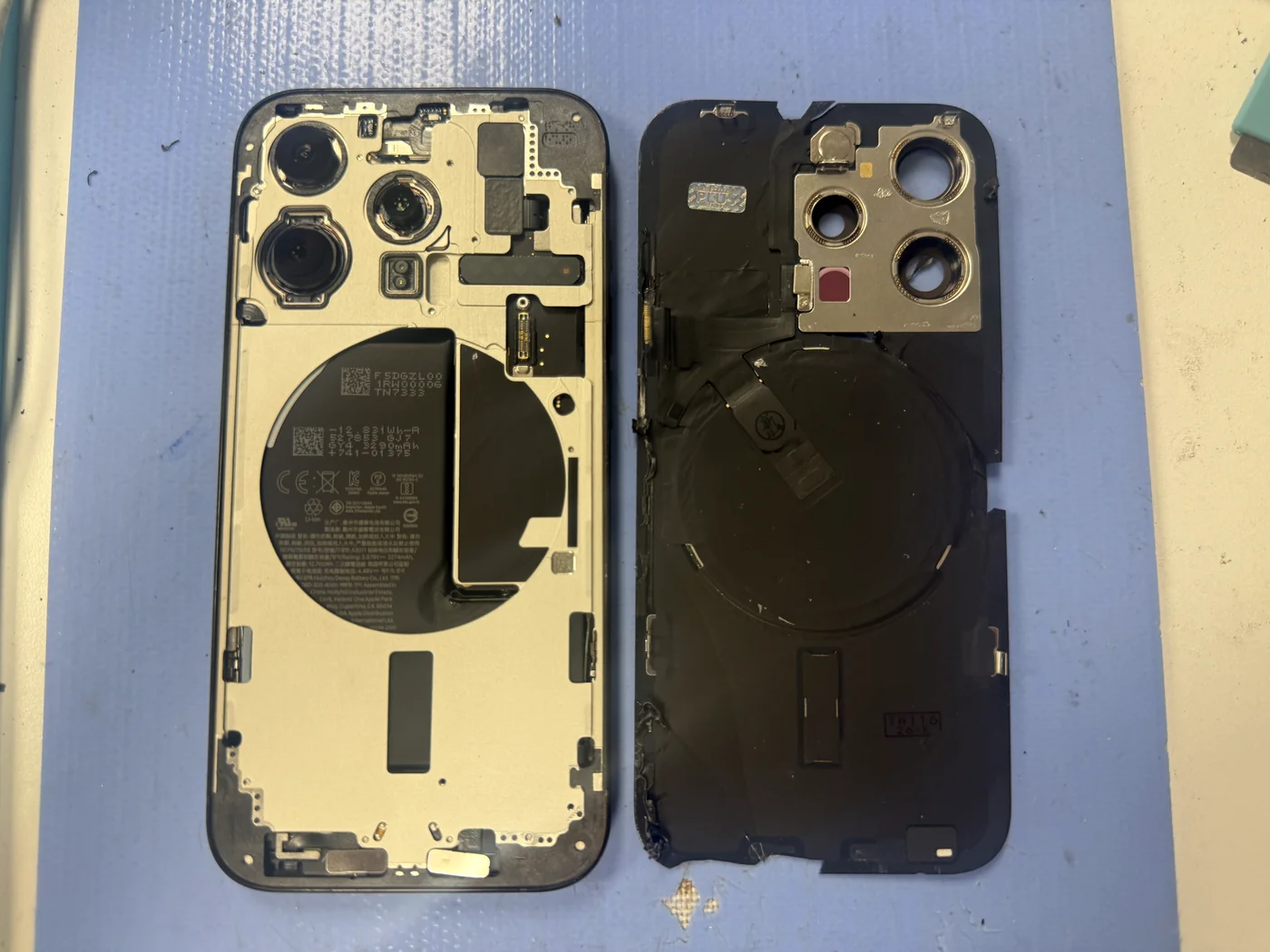 Open iPhone 15 Pro frame next to the removed aftermarket back glass, inner side up
