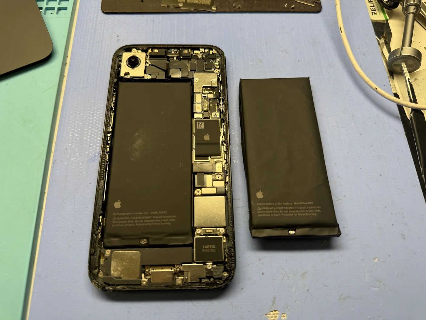 New battery installed in the iPhone 16e with the swollen cell beside it