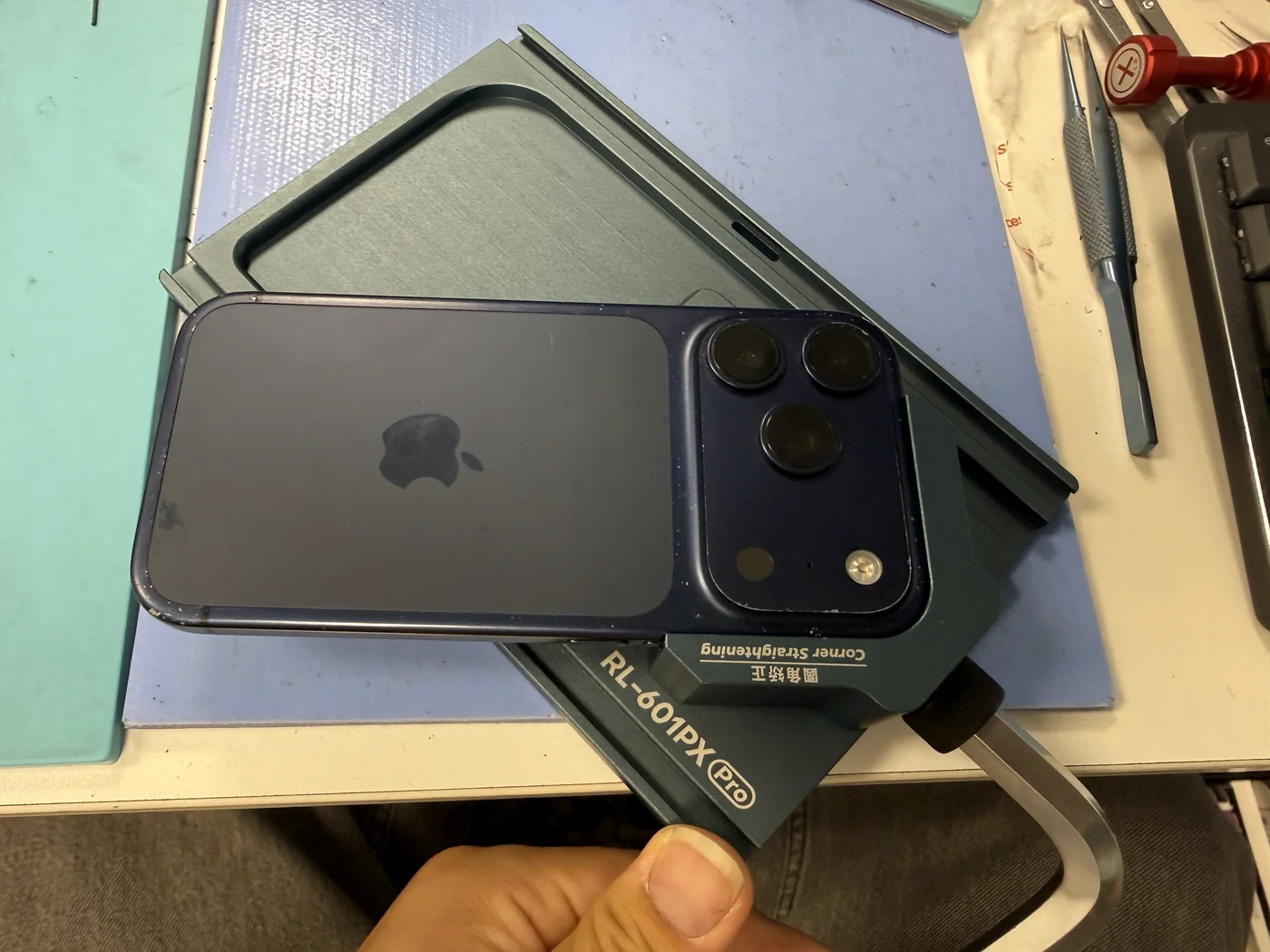 iPhone 17 Pro in a universal corner-straightening tool to fix the dented frame before the new screen
