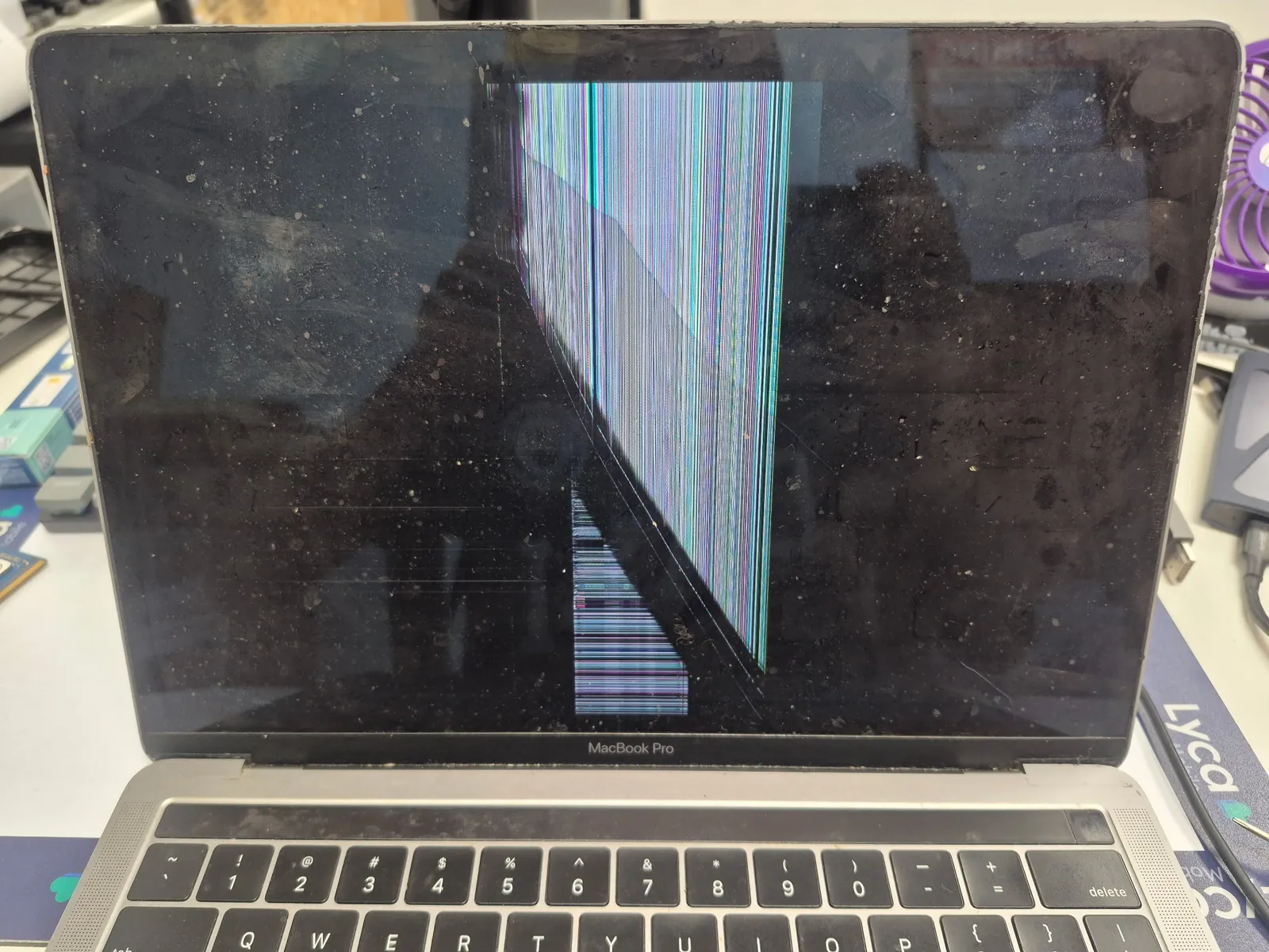 Before repair — MacBook Pro A1989 display covered in colorful vertical lines after drop damage