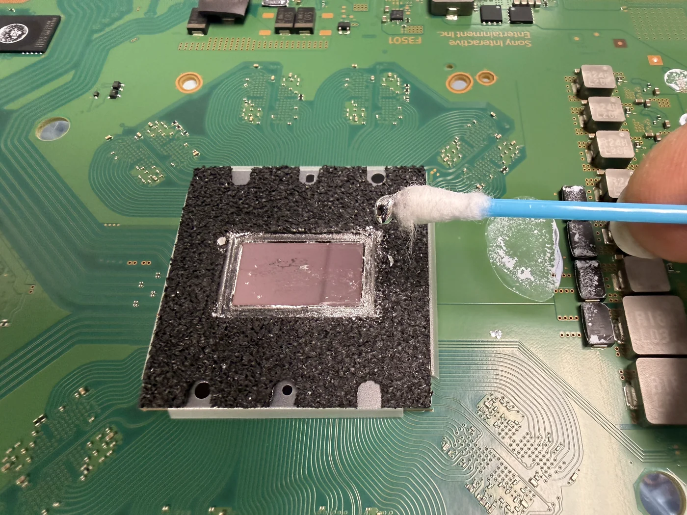 PS5 APU die with old liquid metal cleaned off and fresh liquid metal being applied