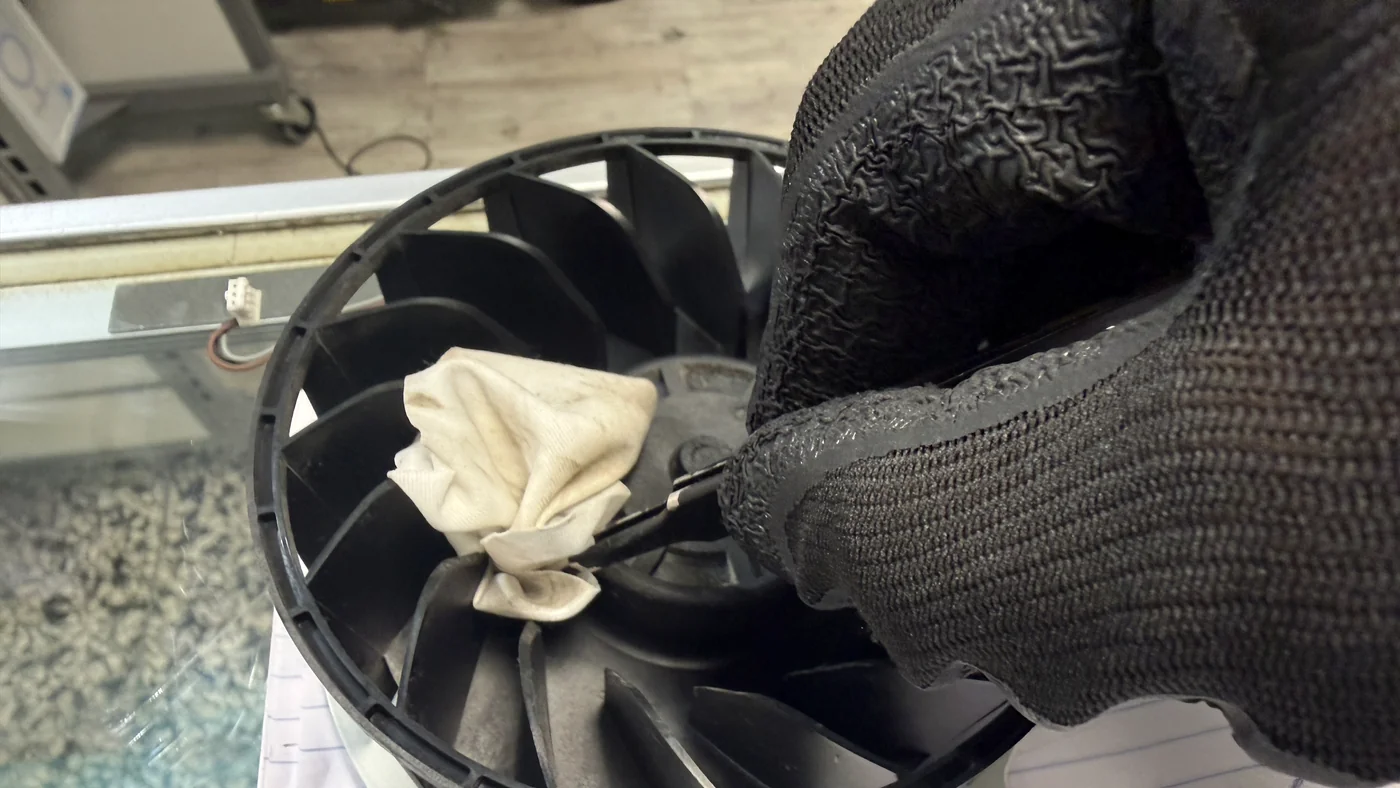 PS5 cooling fan blades being wiped clean during a console cleaning