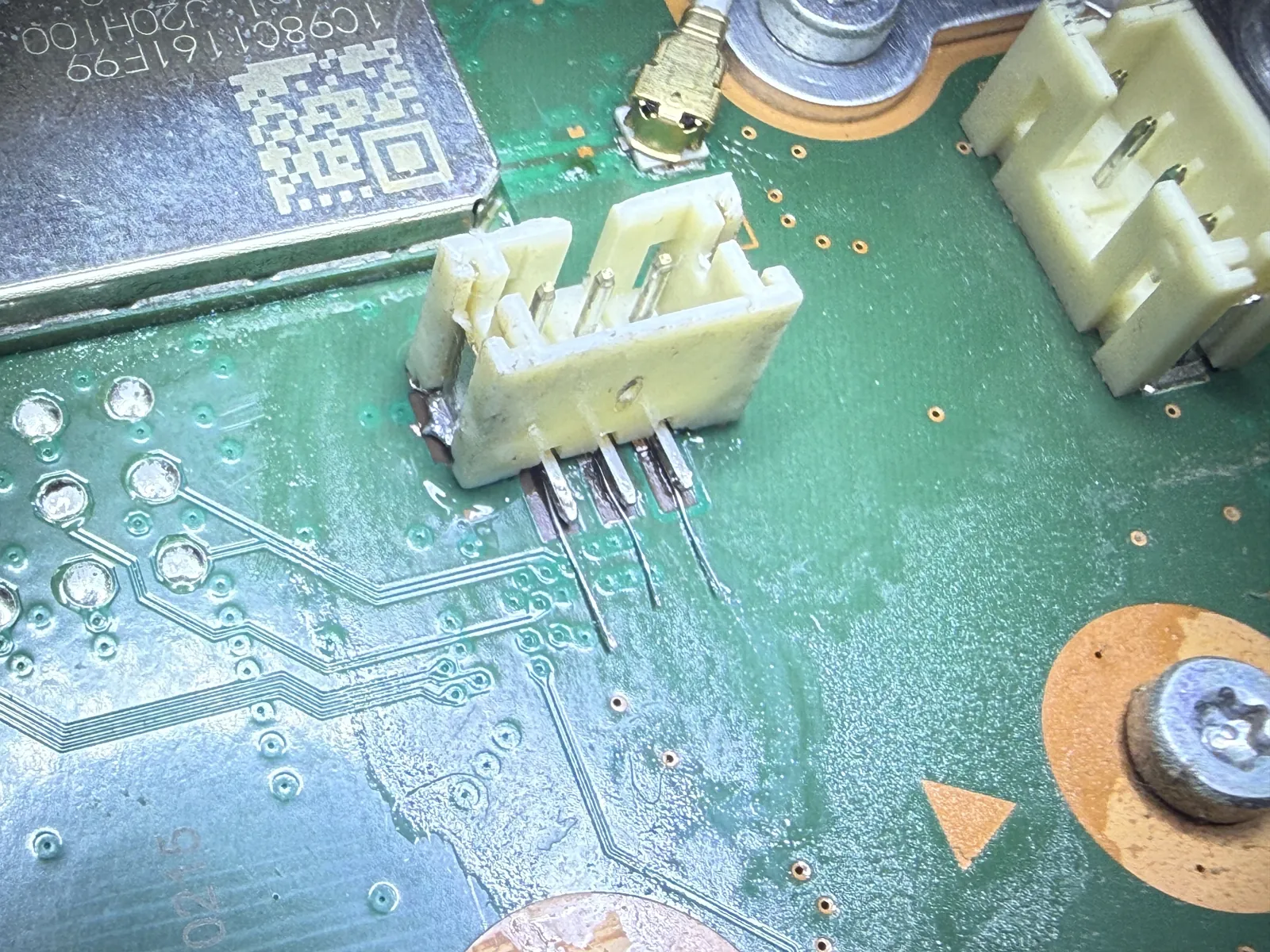 The torn PS5 fan connector soldered back onto the board with its legs extended and rejoined