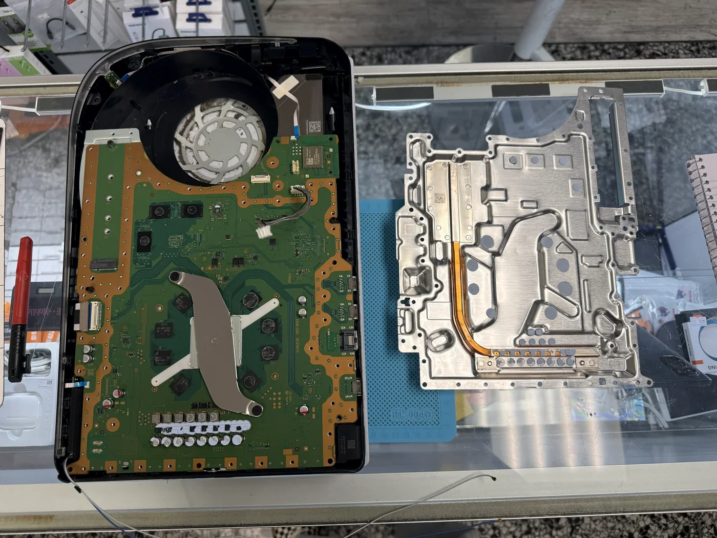PS5 mainboard exposed in the chassis with the heatsink removed beside it, ready for HDMI port replacement