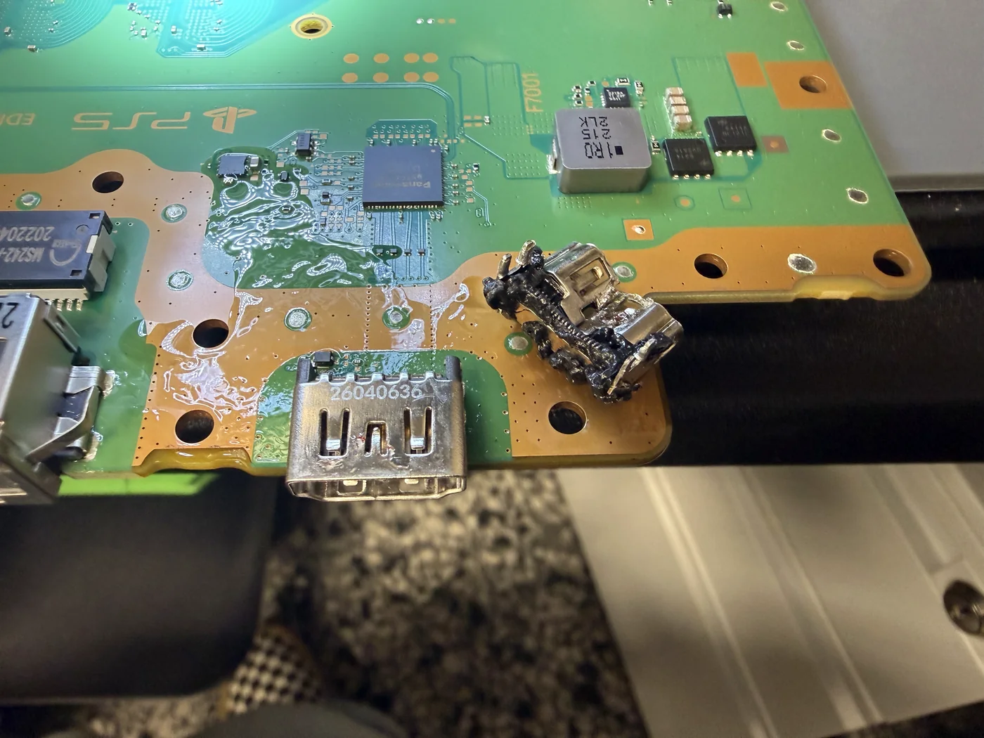 New HDMI port installed and soldered on the PS5 board, with the old damaged port lying beside it