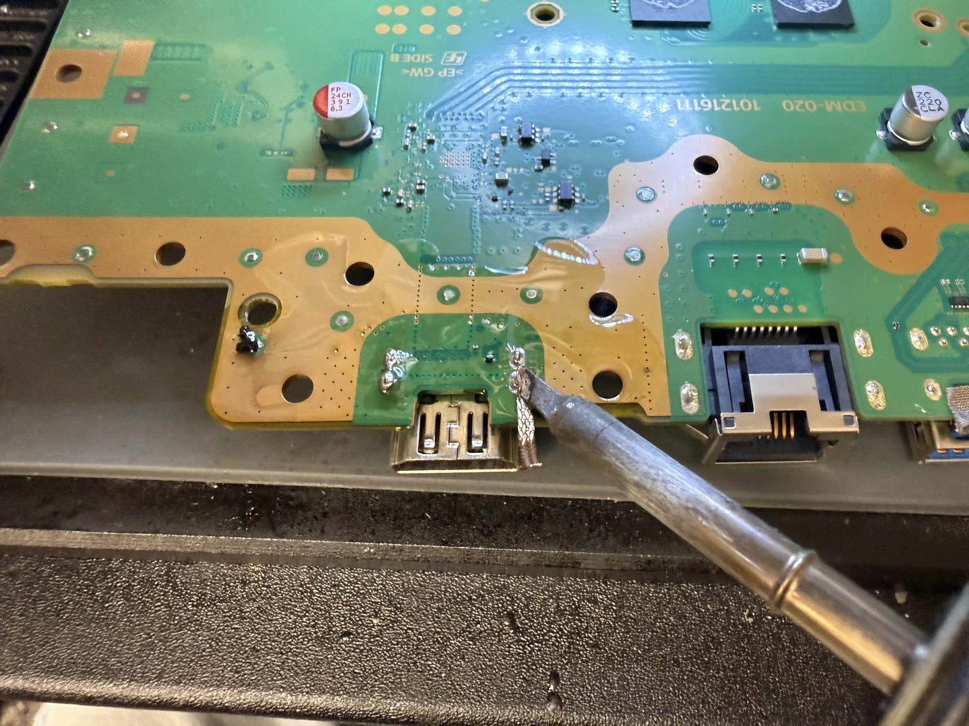 Soldering iron on the shield legs of the damaged PS5 HDMI port, freeing it from the board