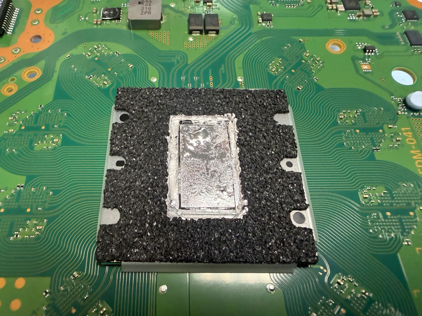 Dried liquid metal pulled away from the center of the APU die on a PS5 Slim main board at check-in