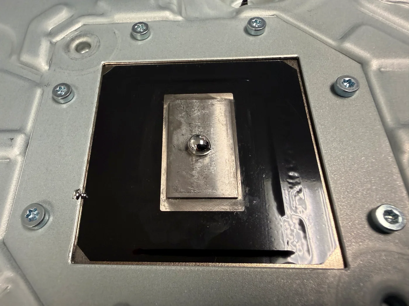 A measured bead of fresh liquid metal on the cleaned bare-metal contact plate of a PS5 Slim heatsink