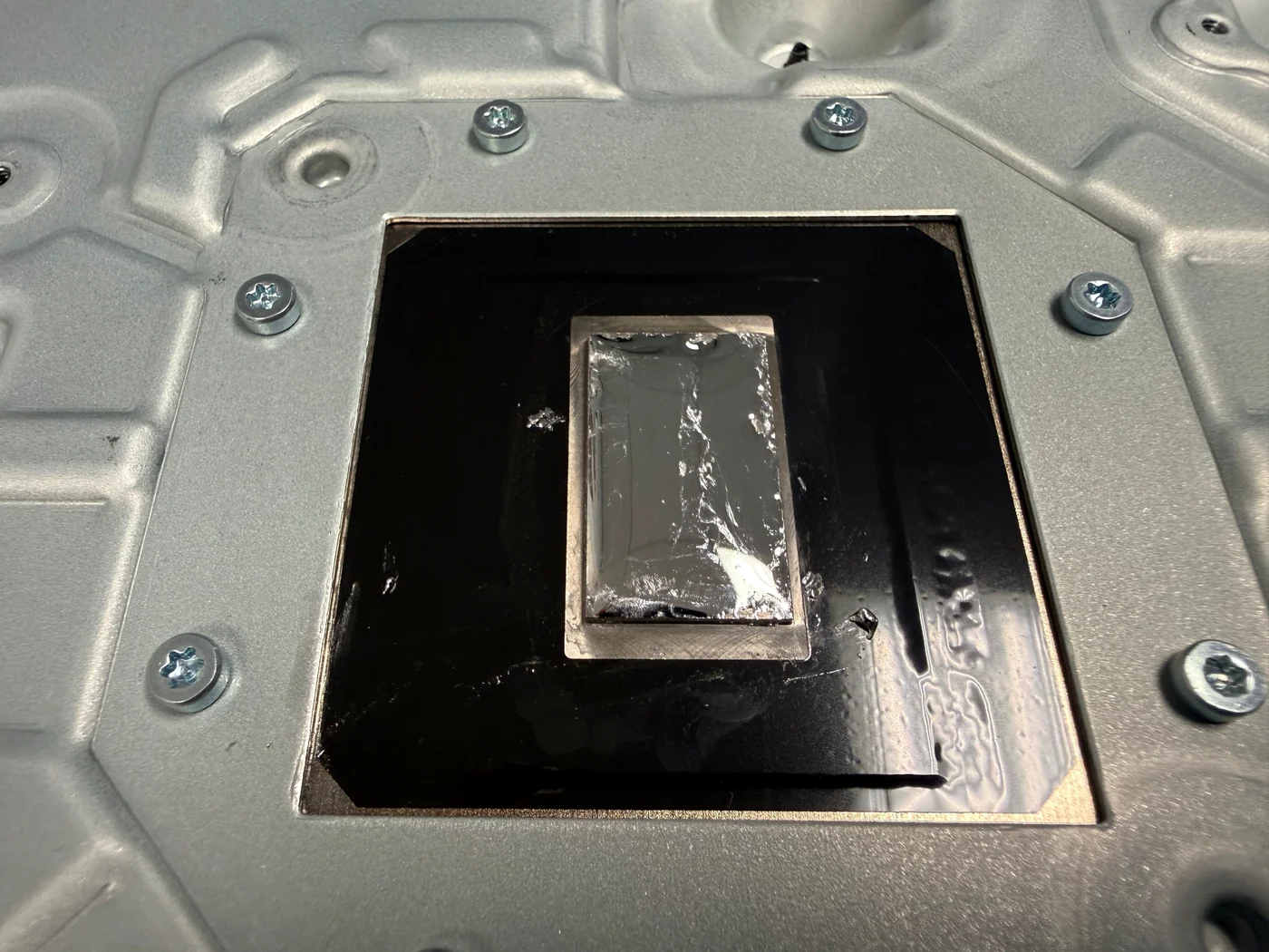 Fresh liquid metal worked out across the full APU contact plate of a PS5 Slim heatsink