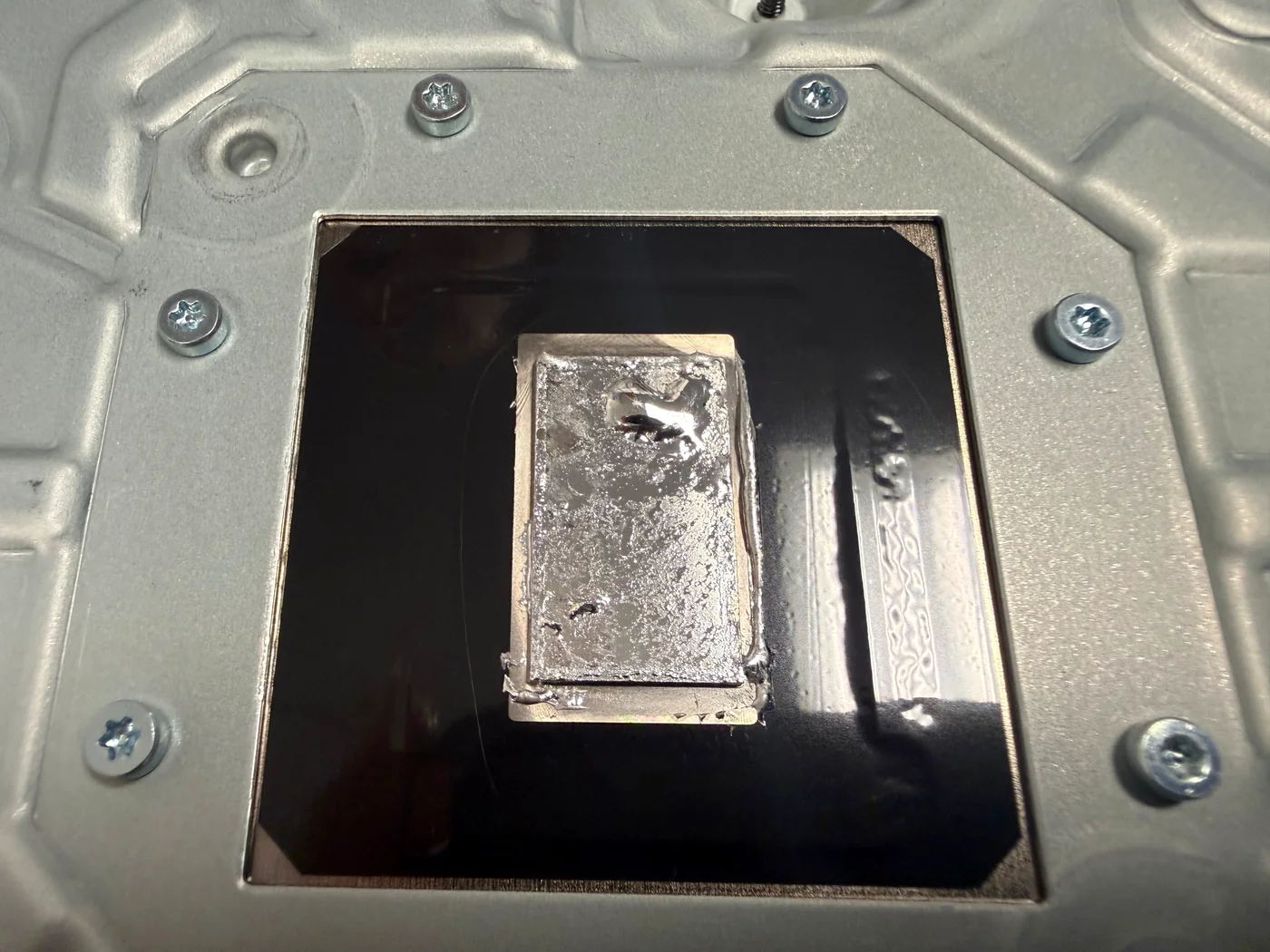 Old liquid metal gone grainy and crept to one edge on the APU contact plate of a PS5 Slim heatsink at check-in