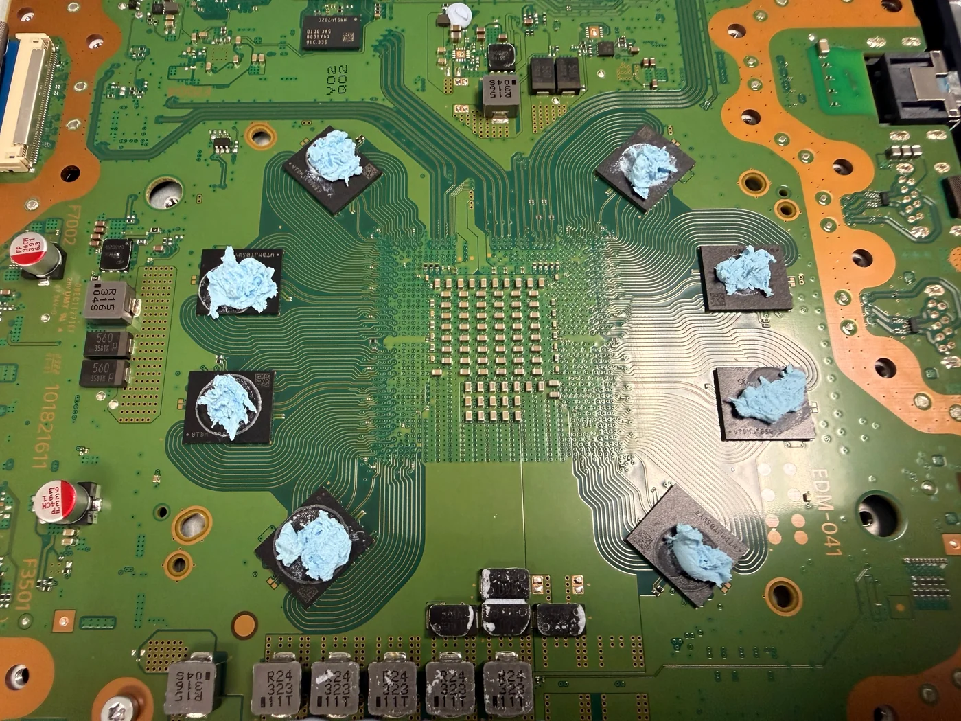 Fresh thermal putty applied to the memory and power chips of a PS5 Slim main board after liquid metal replacement