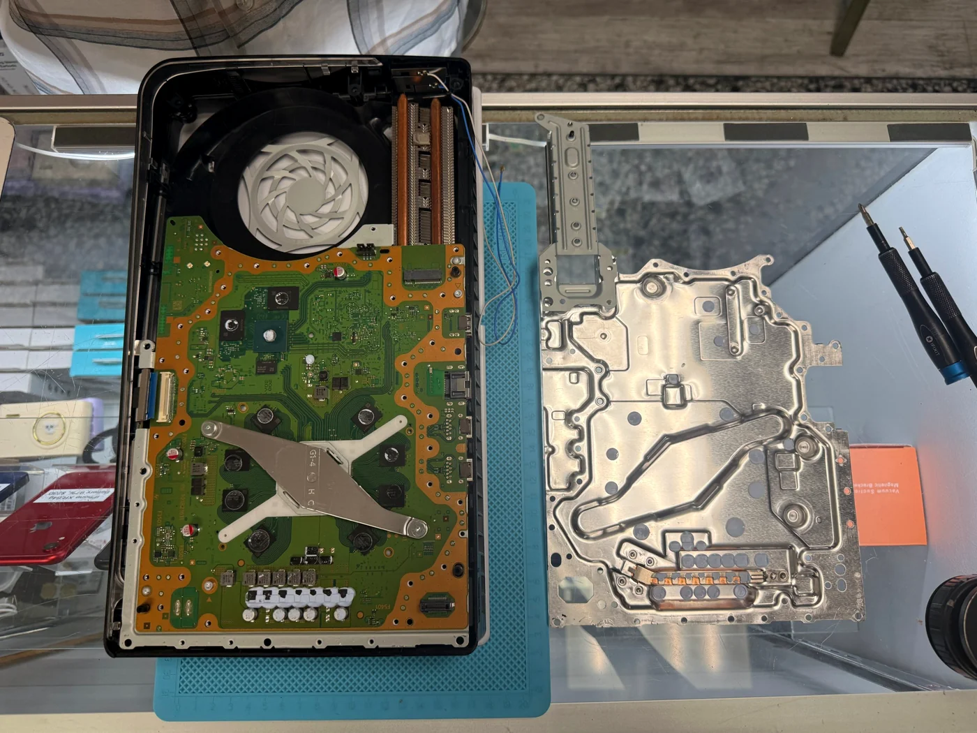 PS5 Slim opened on the bench with the heatsink assembly lifted away from the main board for thermal service
